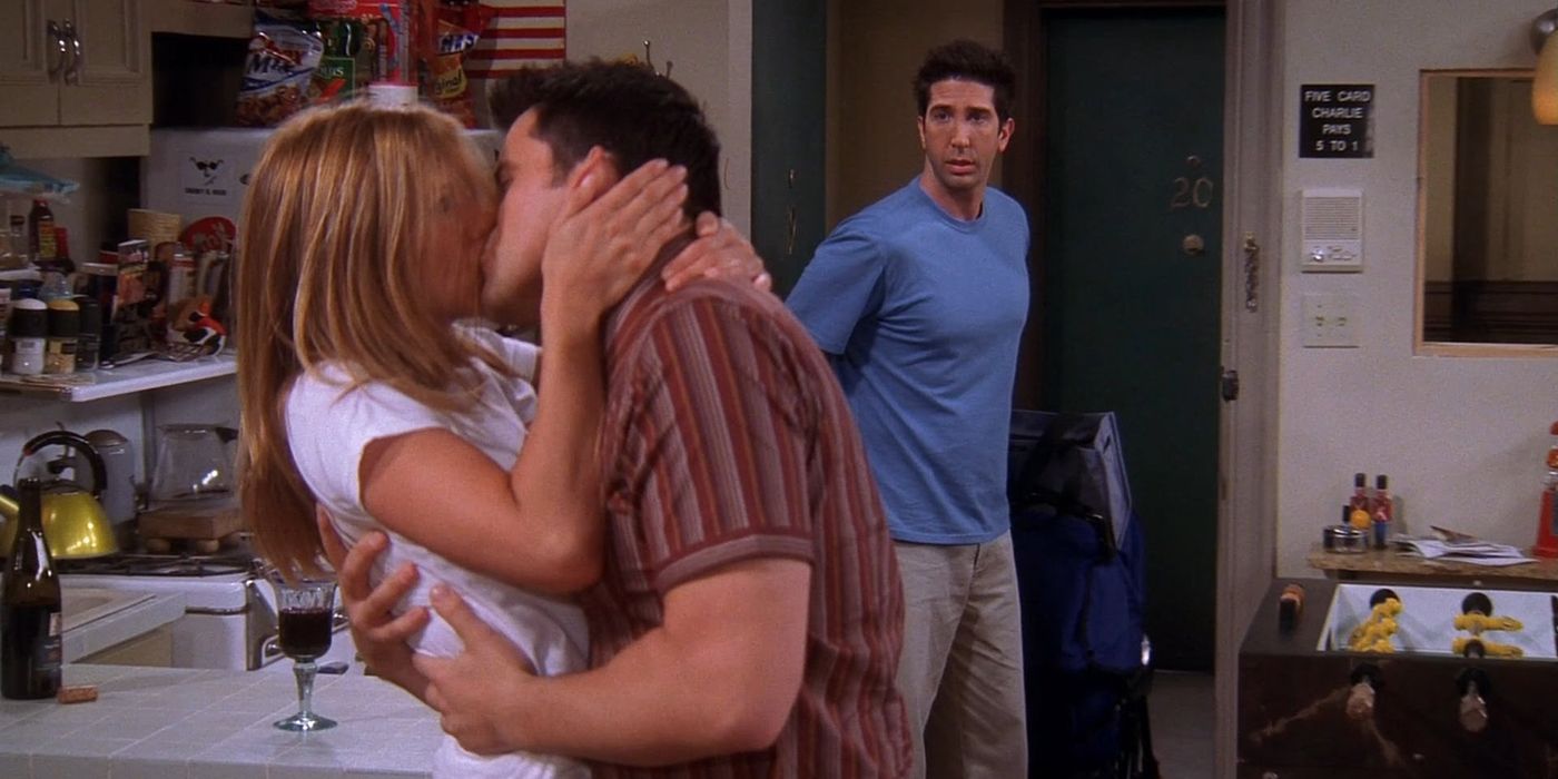 Rachel and Joey kissing as a surprised Ross walks through the door in Friends