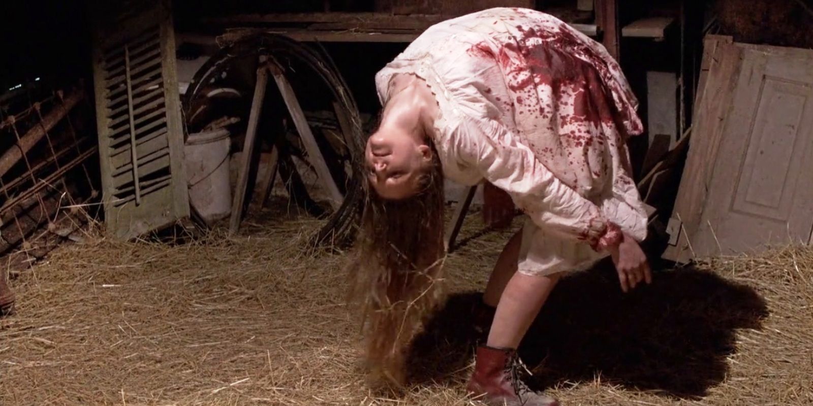 Uma mulher curvada para trás com um vestido manchado de sangue em um celeiro em O Último Exorcismo