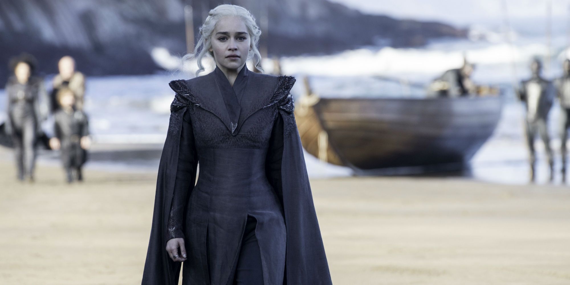 Daenerys Targaryen walks off on shore as Tyrion, Missandei, and others are in the background with a boat
