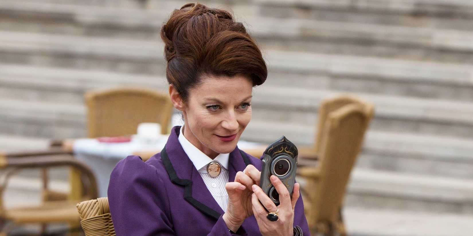 Michelle Gomez as Missy, aka The Master, holding an alien device in Doctor Who.