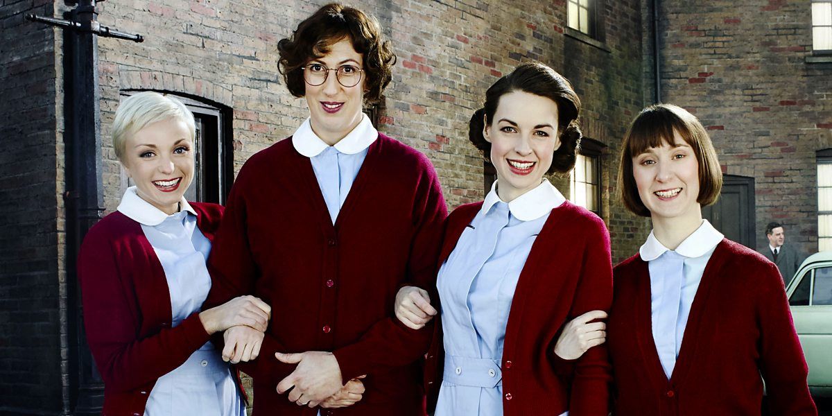 The women link arms in their red sweaters and blue uniforms in Call The Midwife
