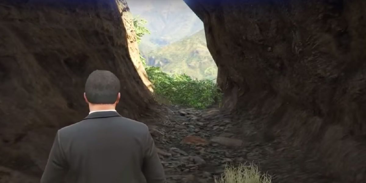 Player approaching the exit of a cave in GTA 5, with light streaming in from outside.