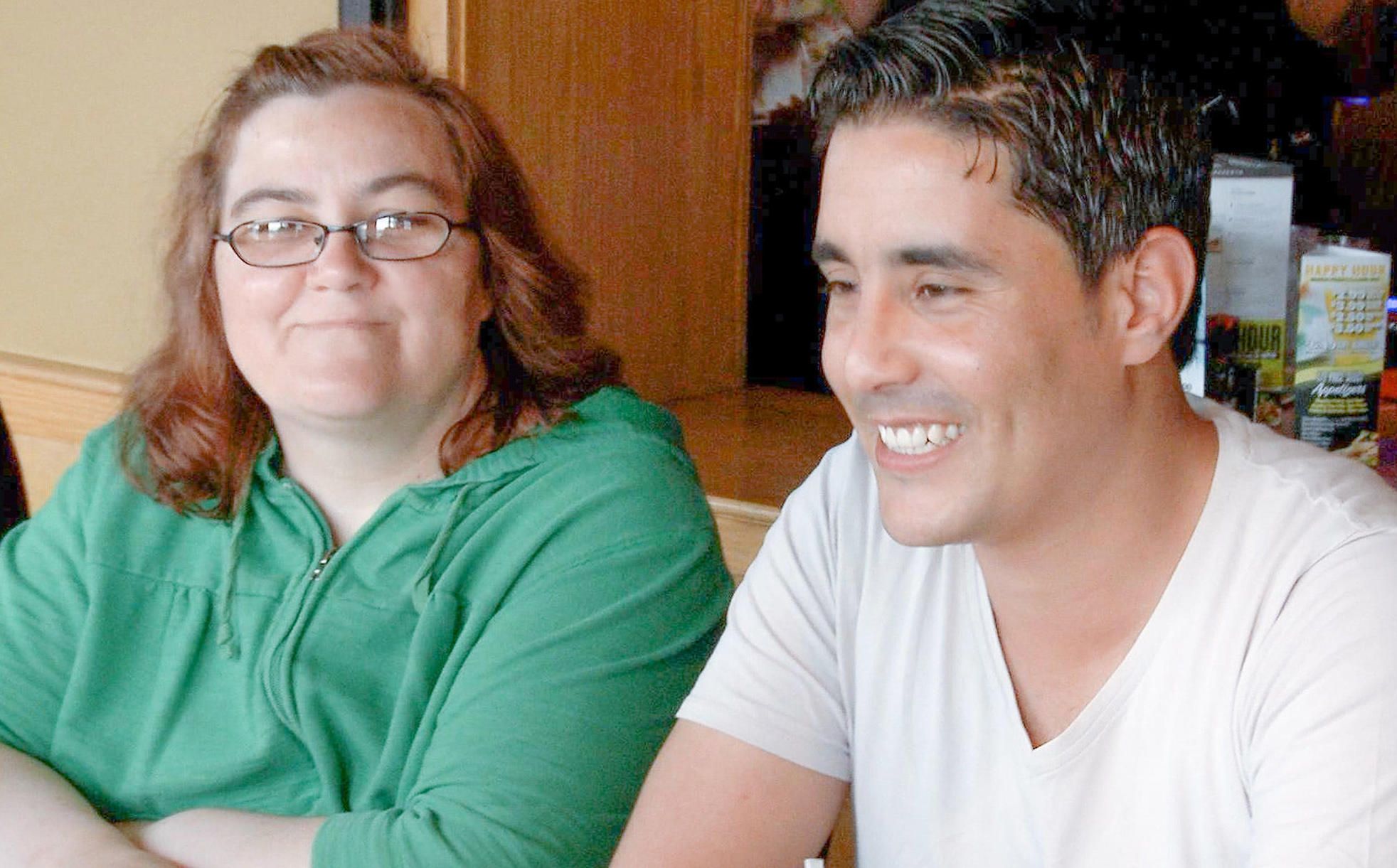 90 Day Fiance Danielle and Mohamed smiling with Danielle in a green top and glasses and Mohamed in a white t-shirt
