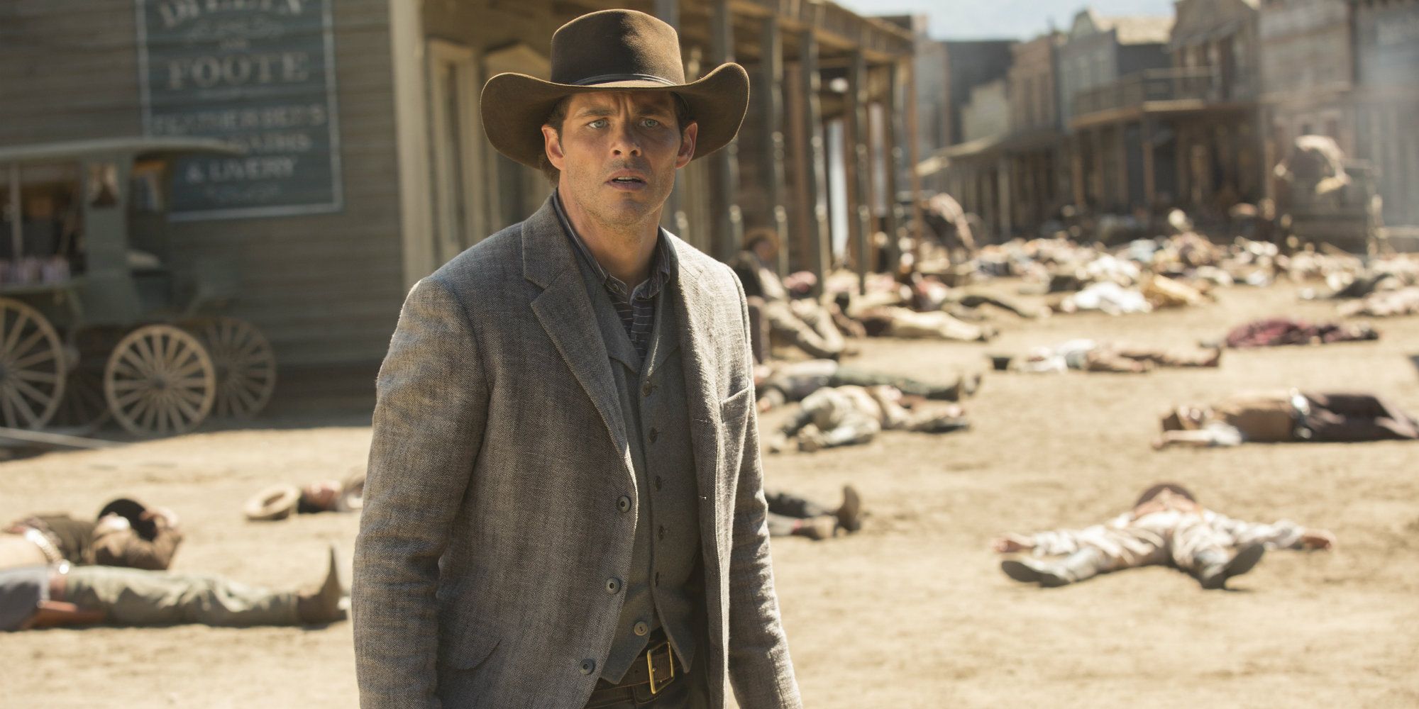 Teddy standing on a street with dead bodies in Westworld