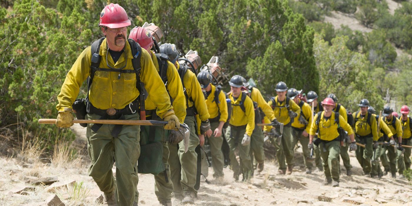 A line of men known as the Granite Mountain Hotshots walking in single file over a mountain in Only the Brave.
