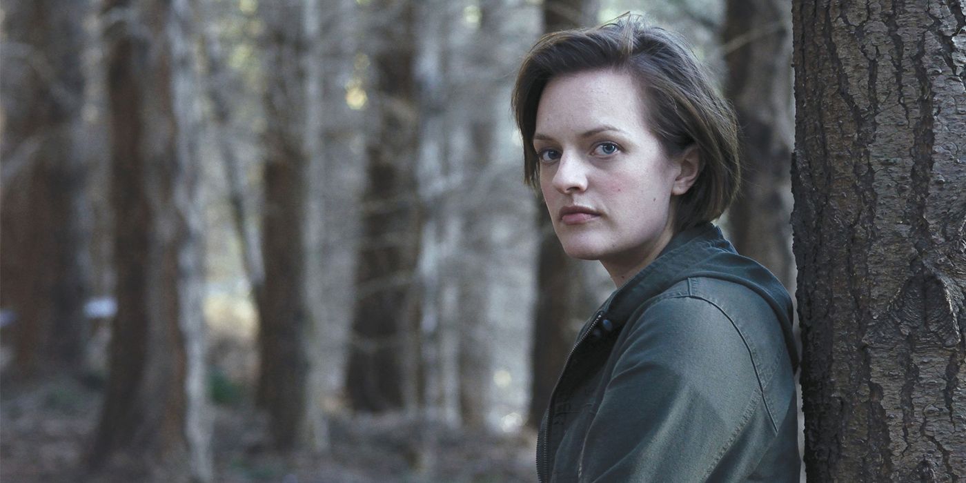 Elisabeth Moss leaning against a tree in a forest in Top of the Lake