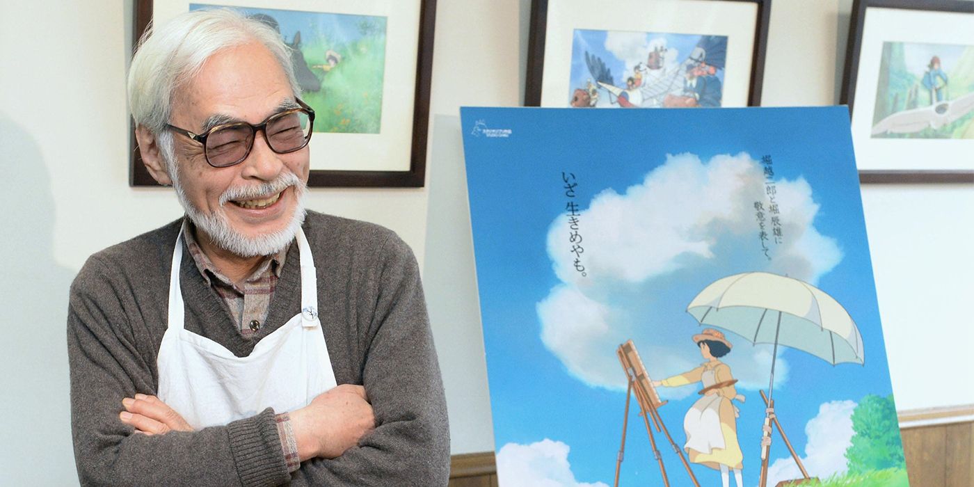 Hayao Miyazaki sentado ao lado de uma pintura