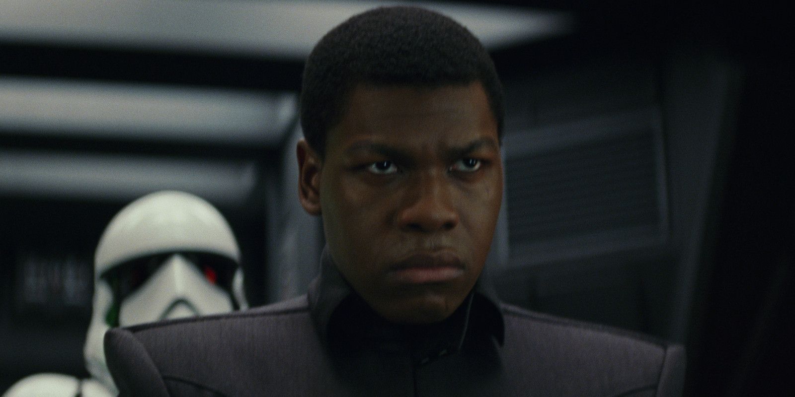 Finn stares angrily forward as a stormtrooper looms behind