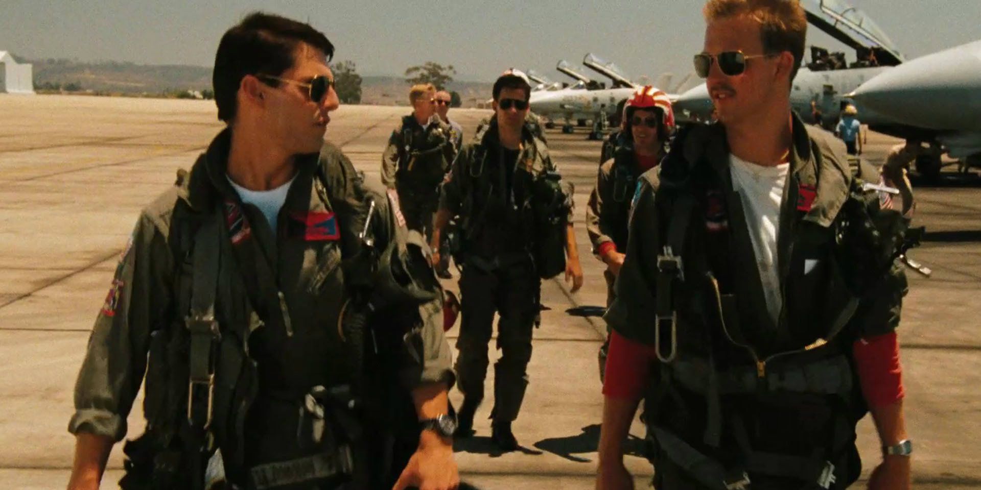 Maverick (Tom Cruise) talks to Goose (Anthony Edwards) as other pilots walk behind them in Top Gun.