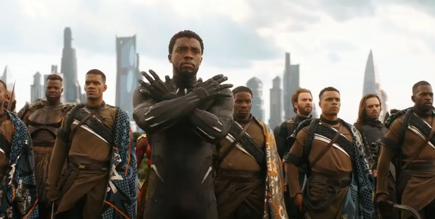 Black Panther in the Wakanda Forever pose in front of Wakandan soldiers.