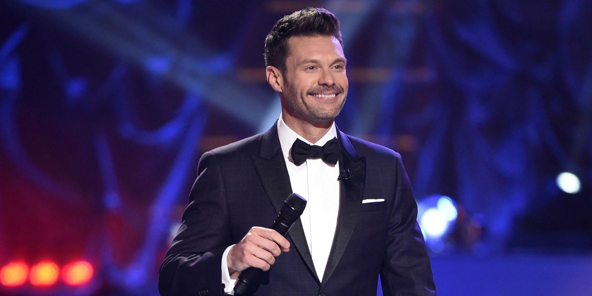 Ryan Seacrest hosting American Idol, holding a mic