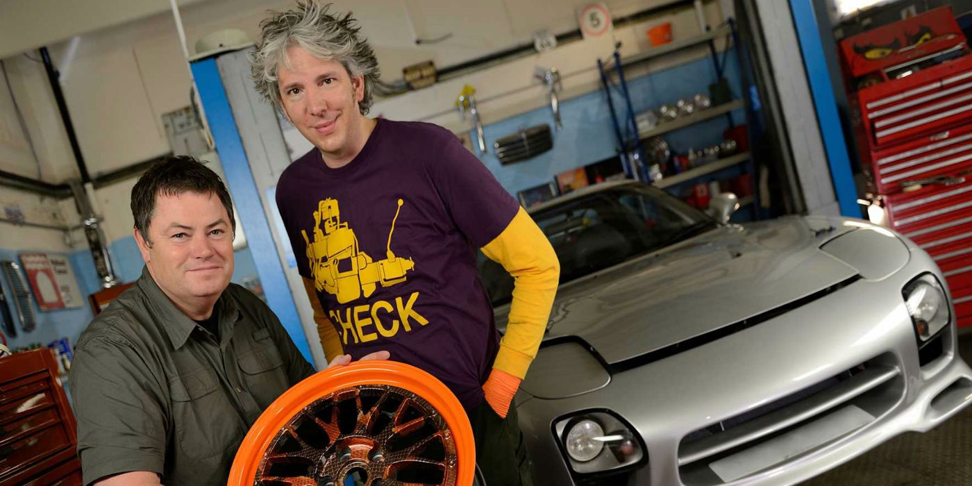 The hosts of the show Wheeler Dealers posing next to a car.