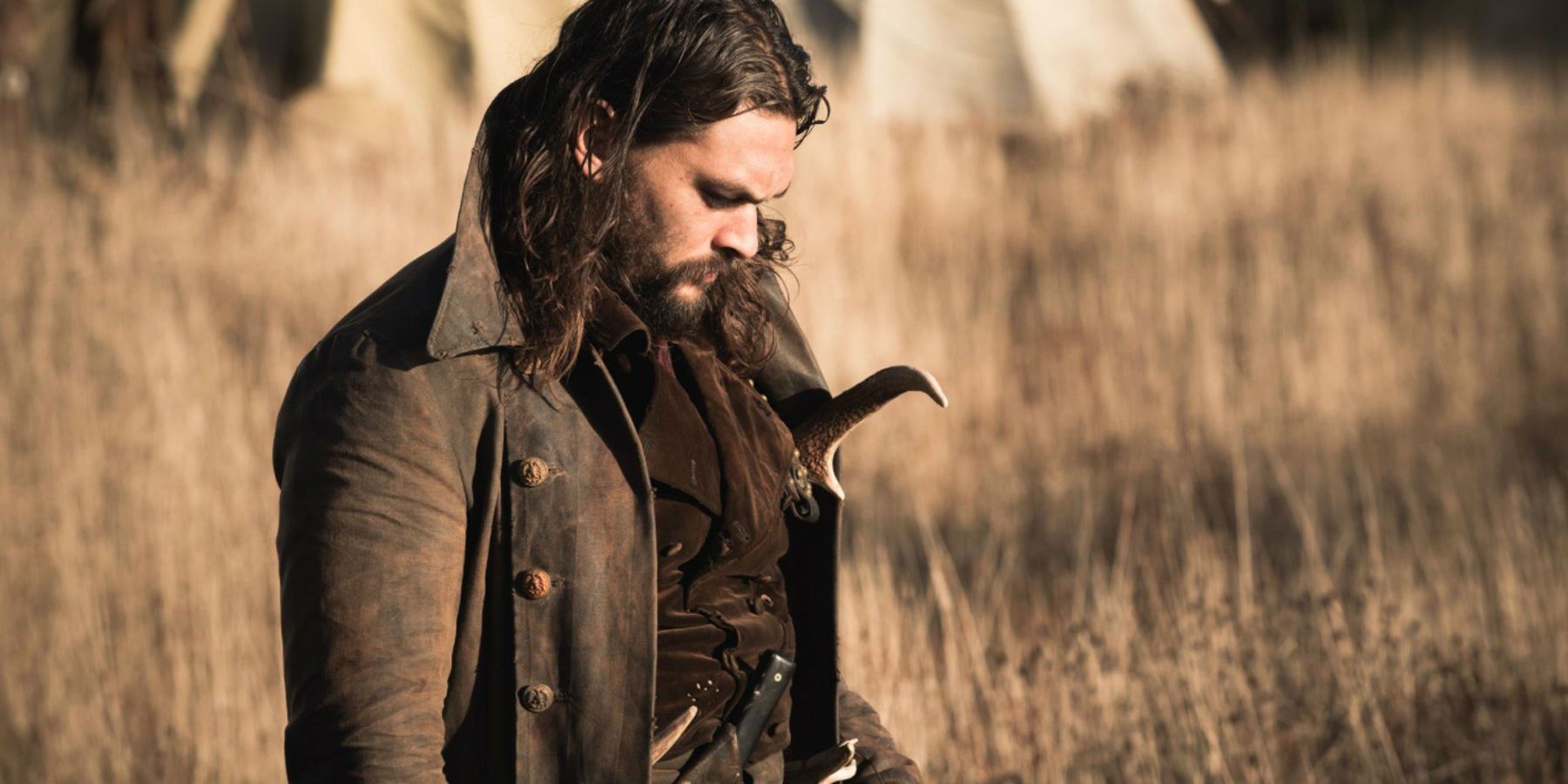 Jason Momoa as Declan Harp with his head down in a field in Frontier