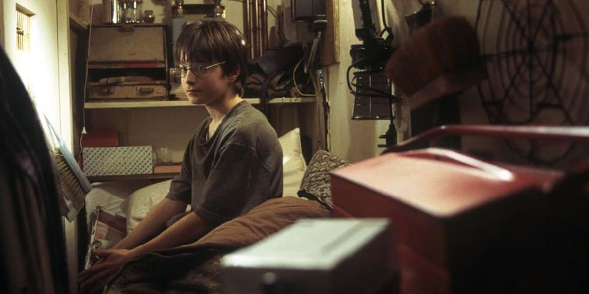Harry Potter sitting in his bed in cupboard under stairs
