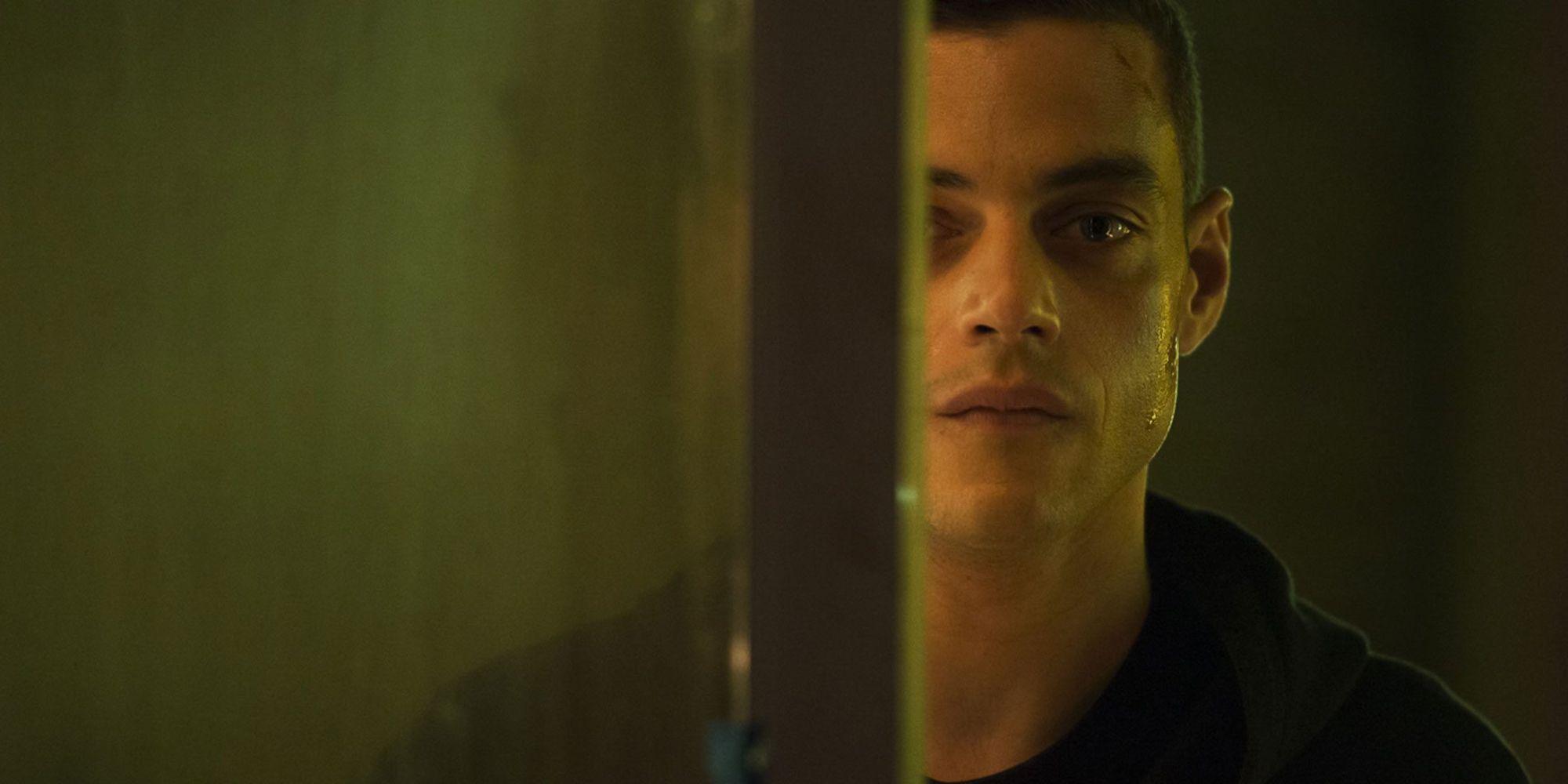 Rami Malek in Mr. Robot looking off to the side with a pole covering part of his face.