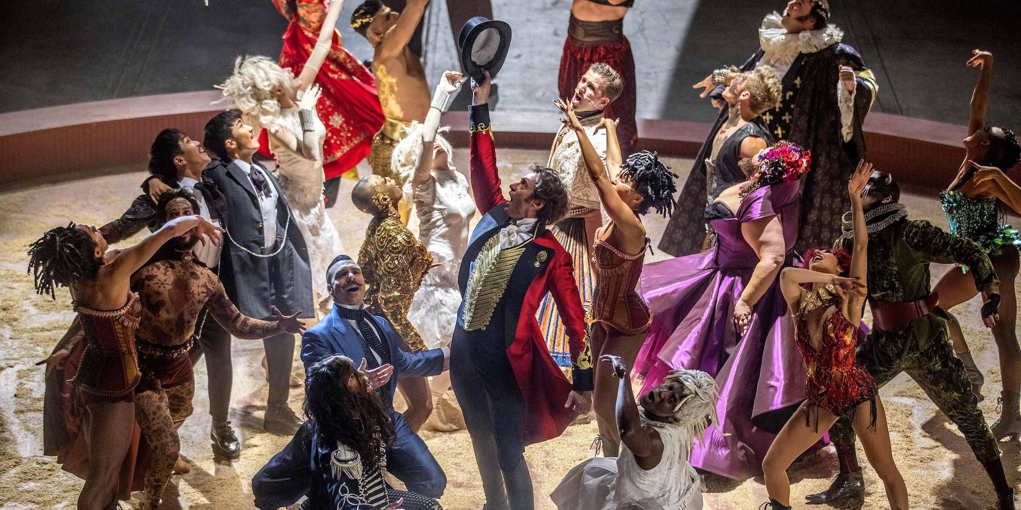 Hugh Jackman singing and surrounded by members of a circus troupe