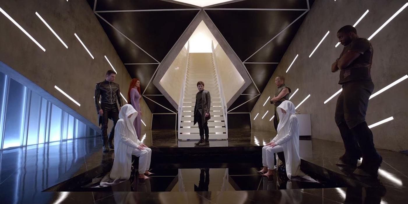 Inhumans members stand around two seated figures wearing white robes in the Inhumans TV series.