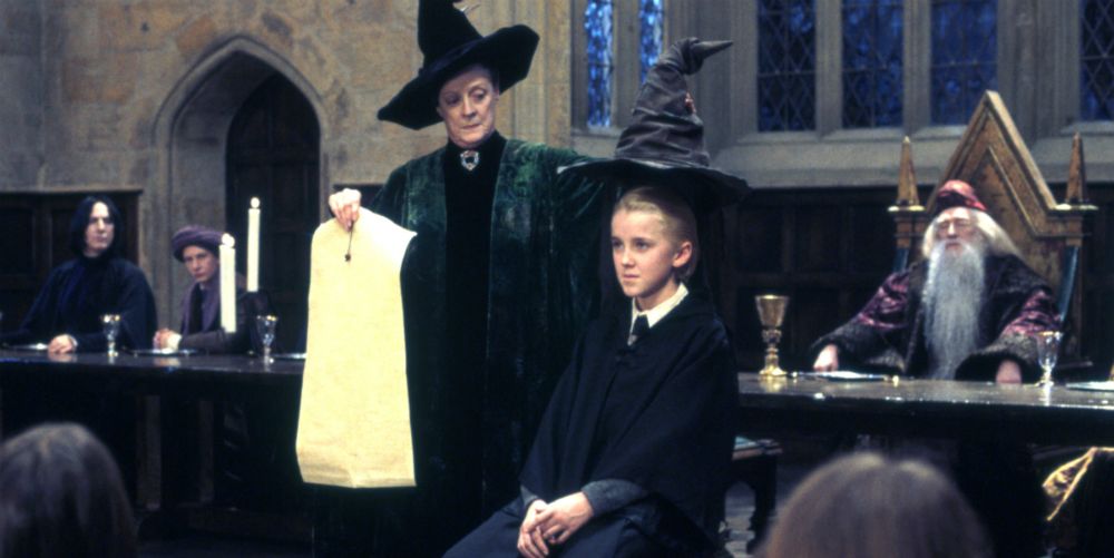 Minerva McGonagall holds the sorting hat above Draco Malfoy in Harry Potter and the Sorcerer's Stone.