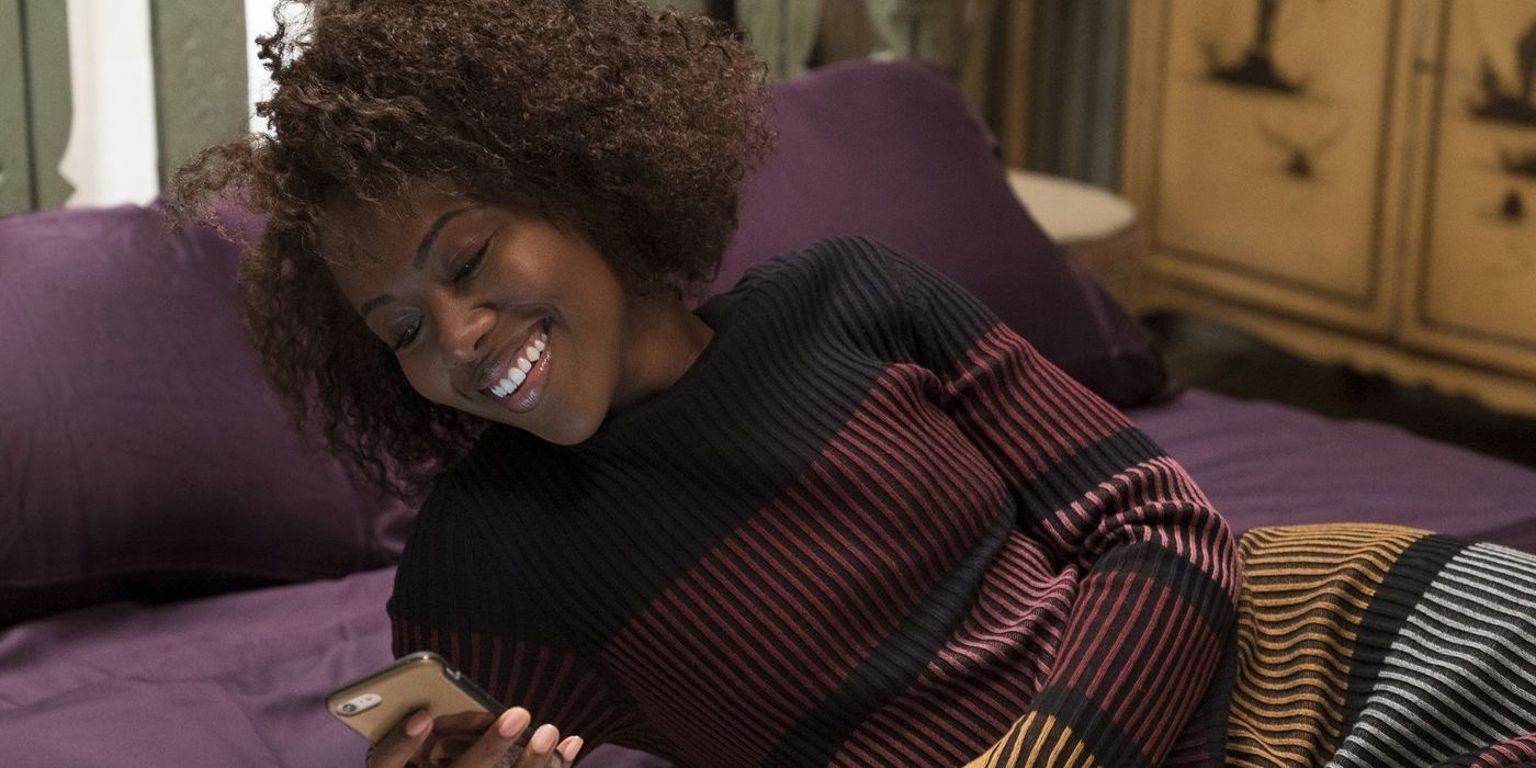  DeWanda Wise as Nola Darling, lying in bed and smiling as she looks at a phone inShe's Gotta Have It