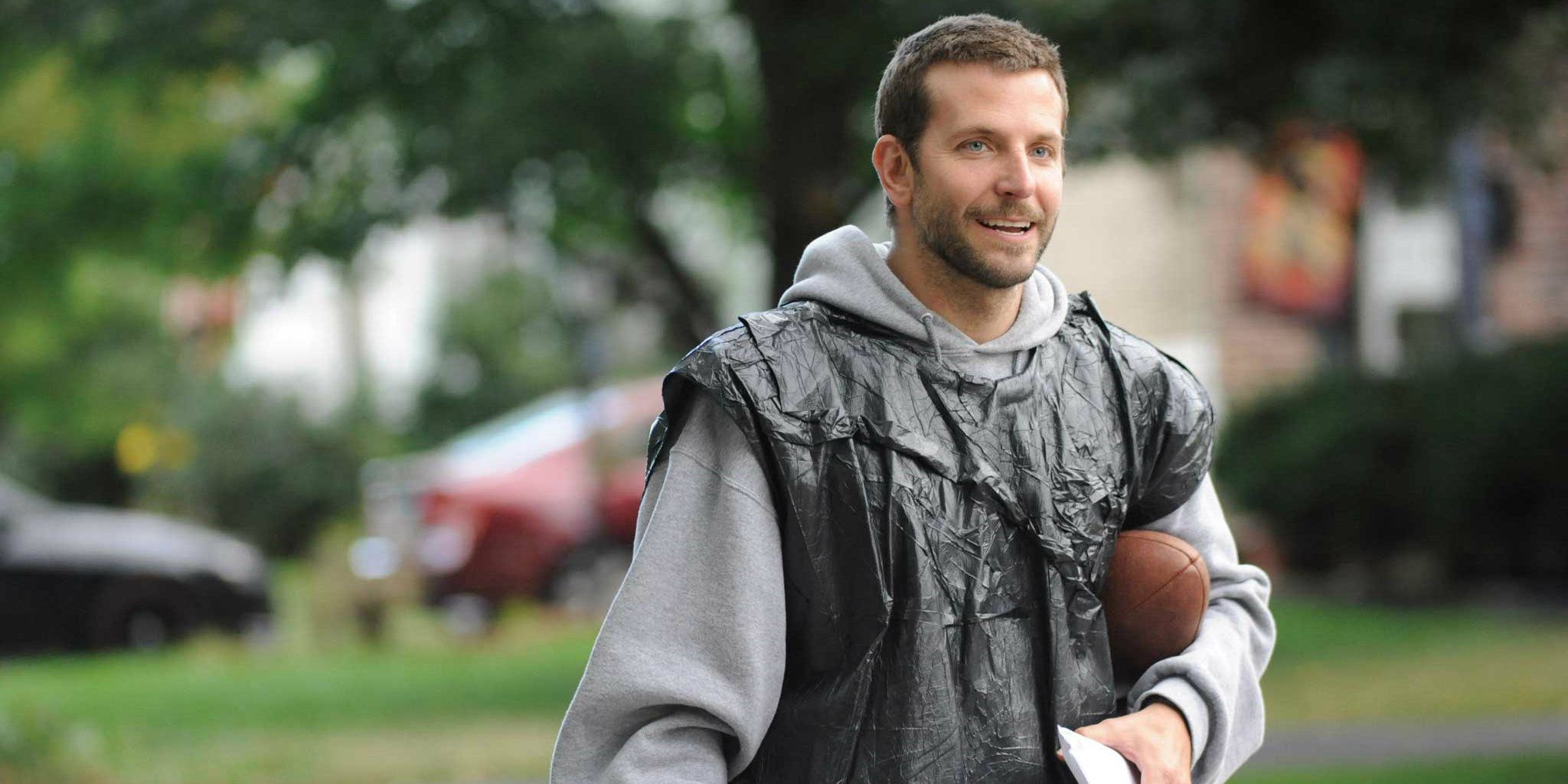 Bradley Cooper wearing a trash bag and holding a football in Silver Linings Playbook.