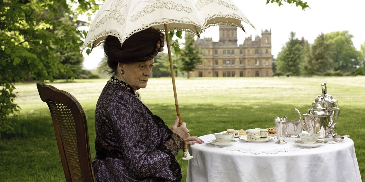 Violet Crawley sitting in the garden under a parasol on Downton Abbey