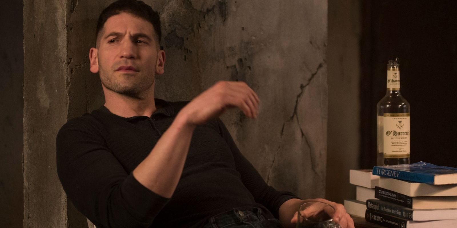 Frank Castle sits at a table with a drink in The Punisher