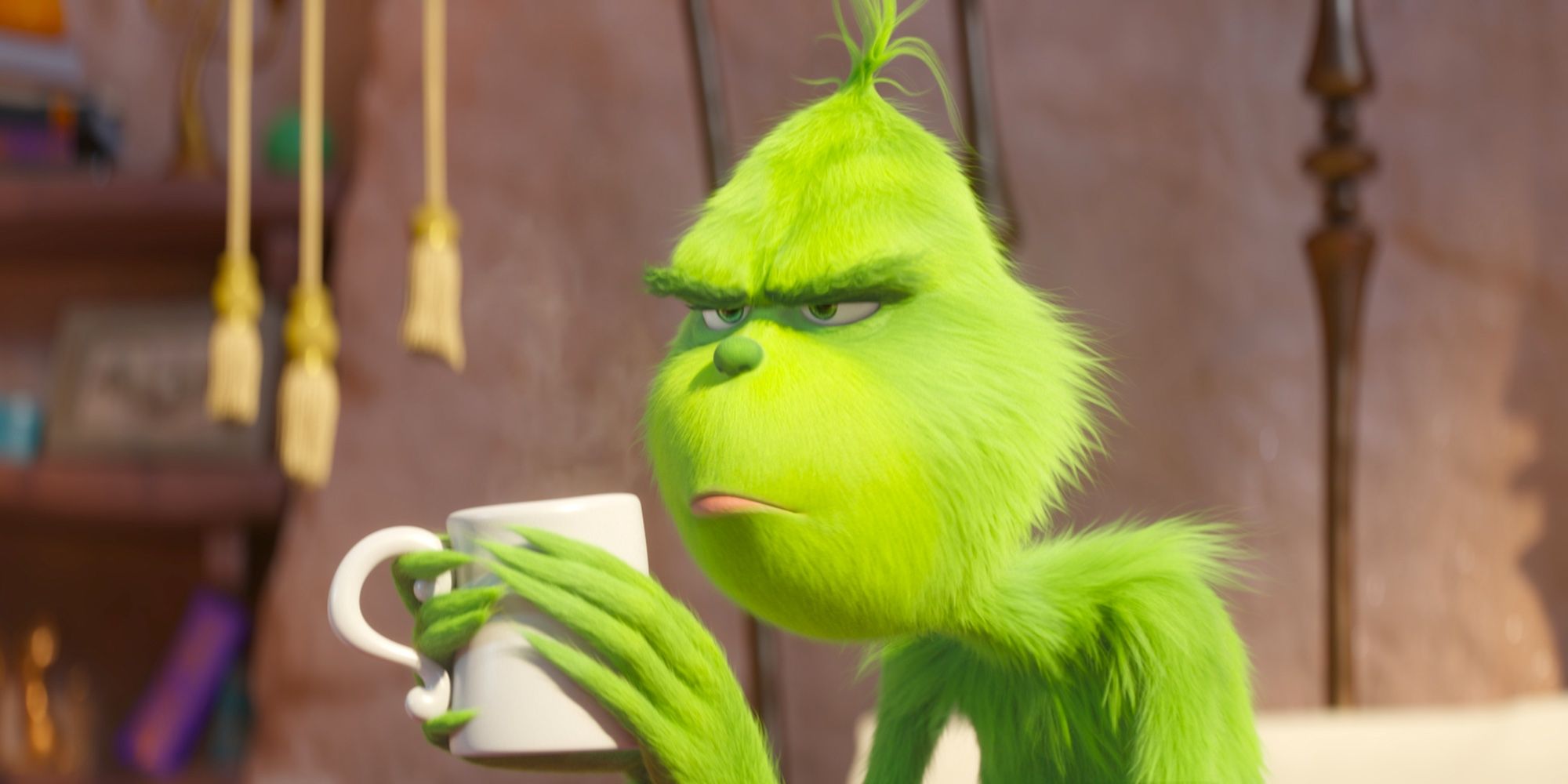 The Grinch making a grouchy face while holding a mug