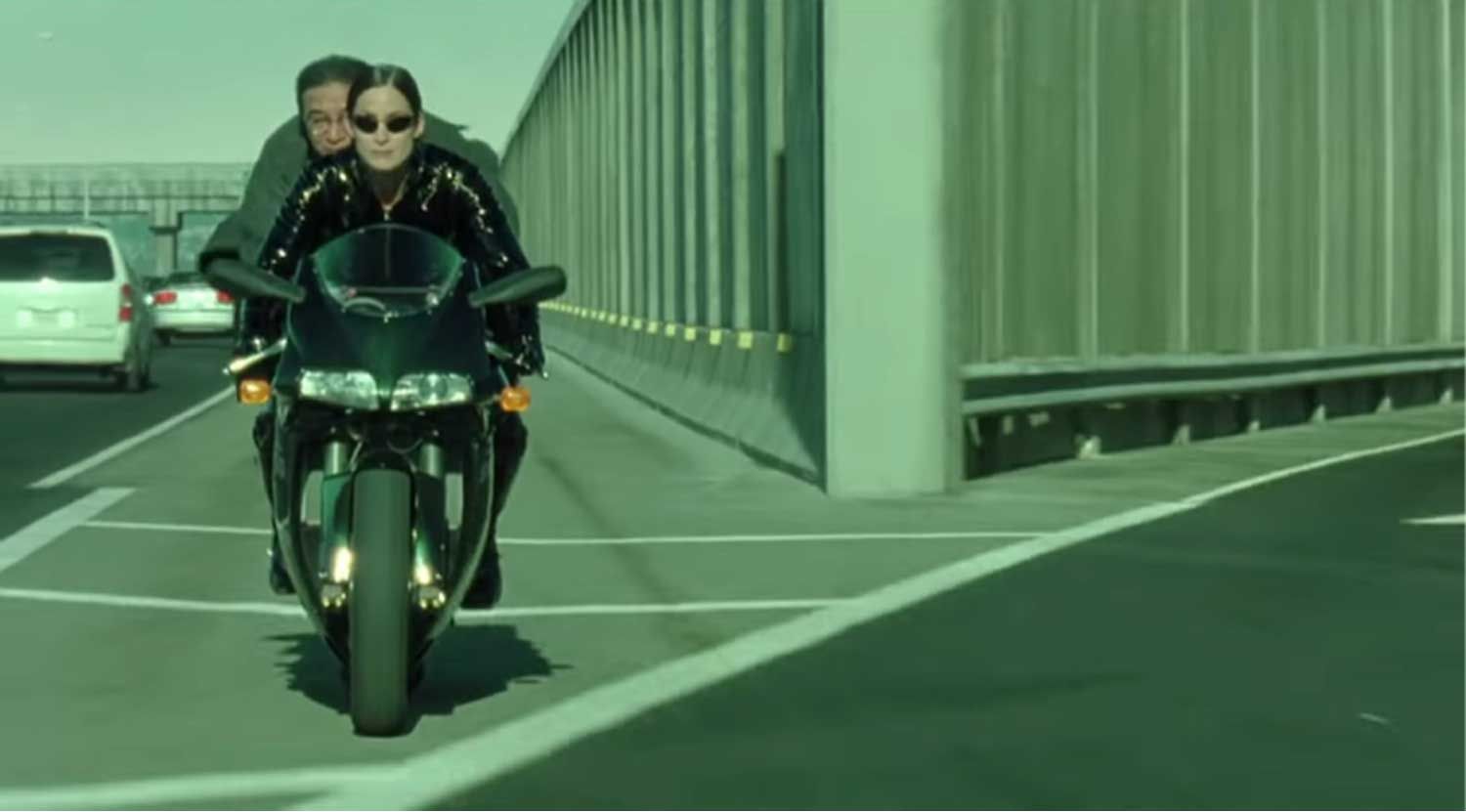 Carrie Anne Moss driving a motorcycle