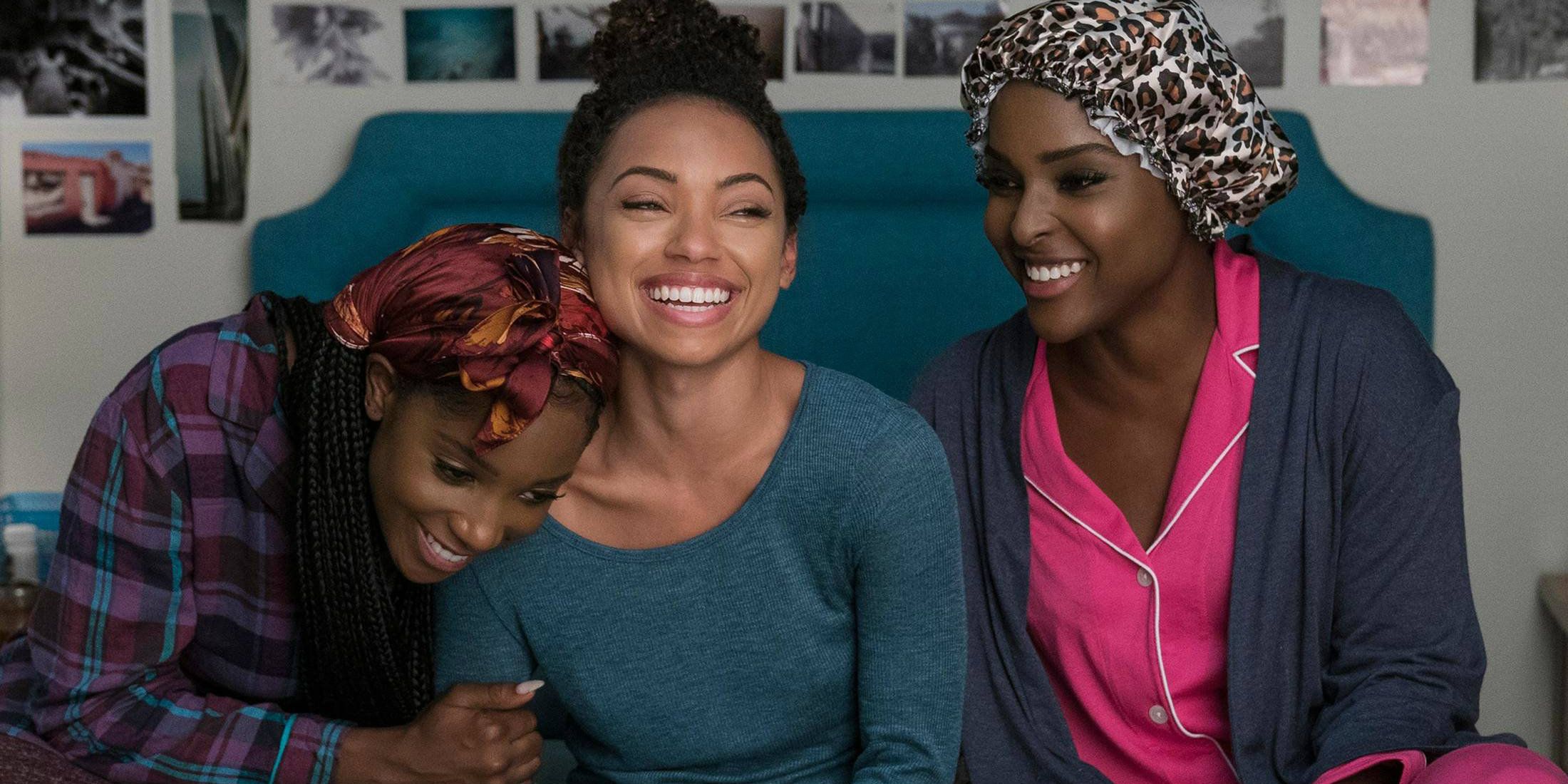 Three girls laughing and hugging on a bed in Dear White People
