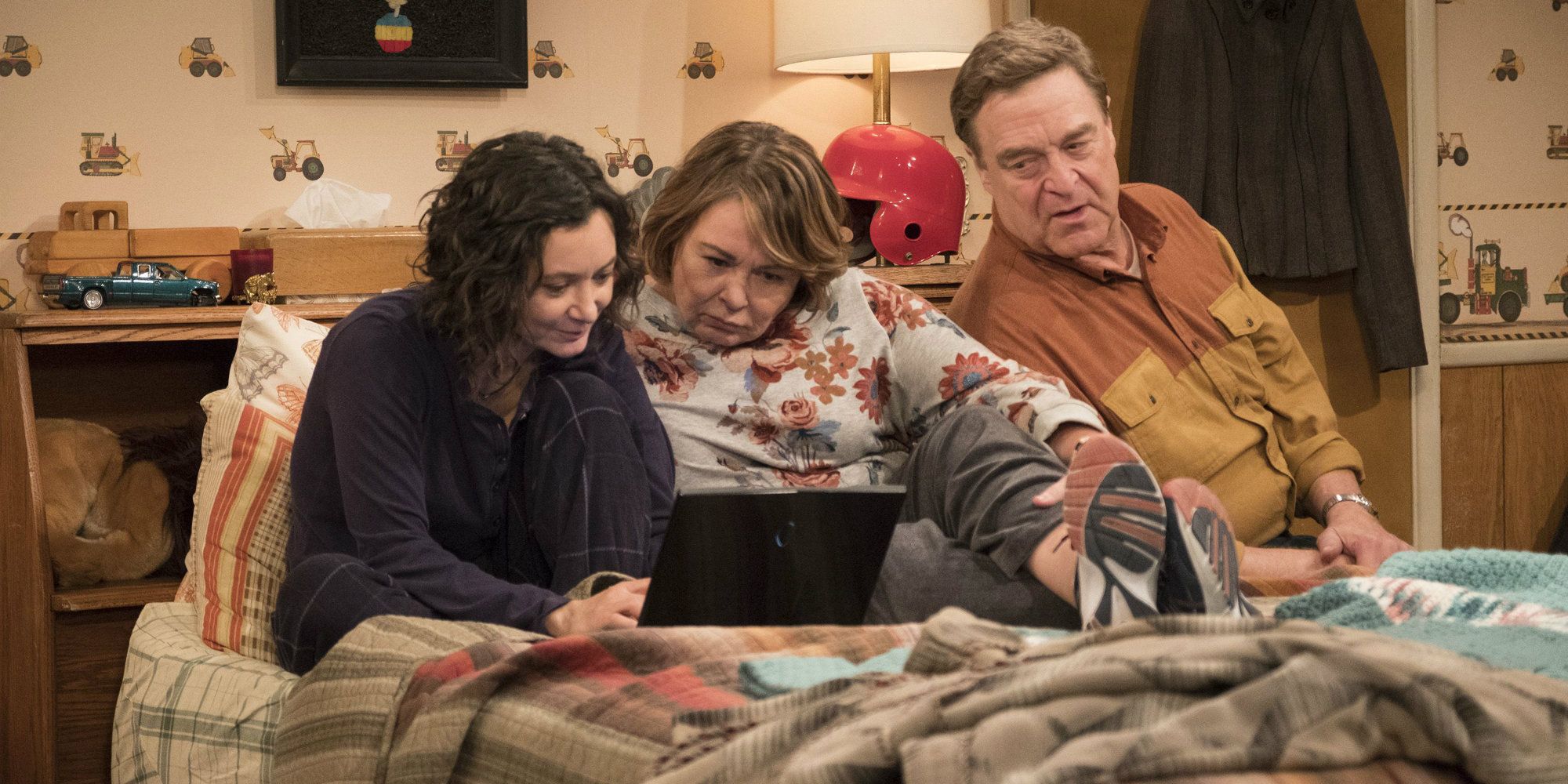 Roseanne and her husband with Darlene watching something in bed in Roseanna