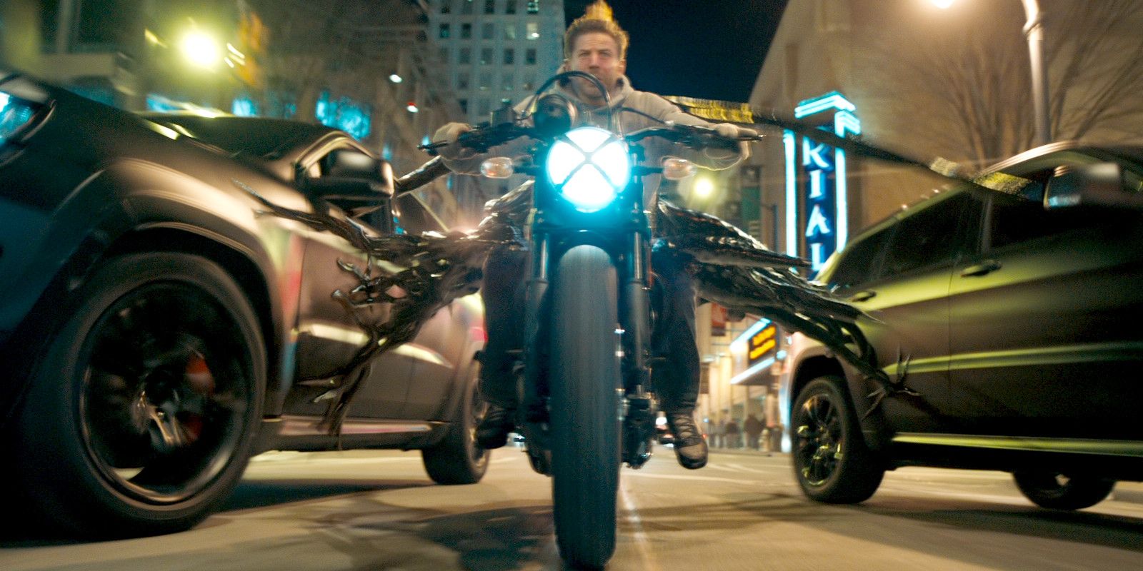 Venom extends his black goo webbing while Eddie Brock rides a motorcycle in the 2018 movie