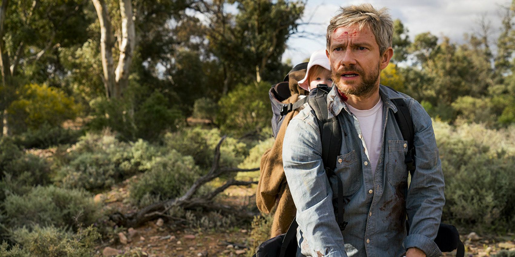 Martin Freeman looking off-camra with a baby on his back in Cargo