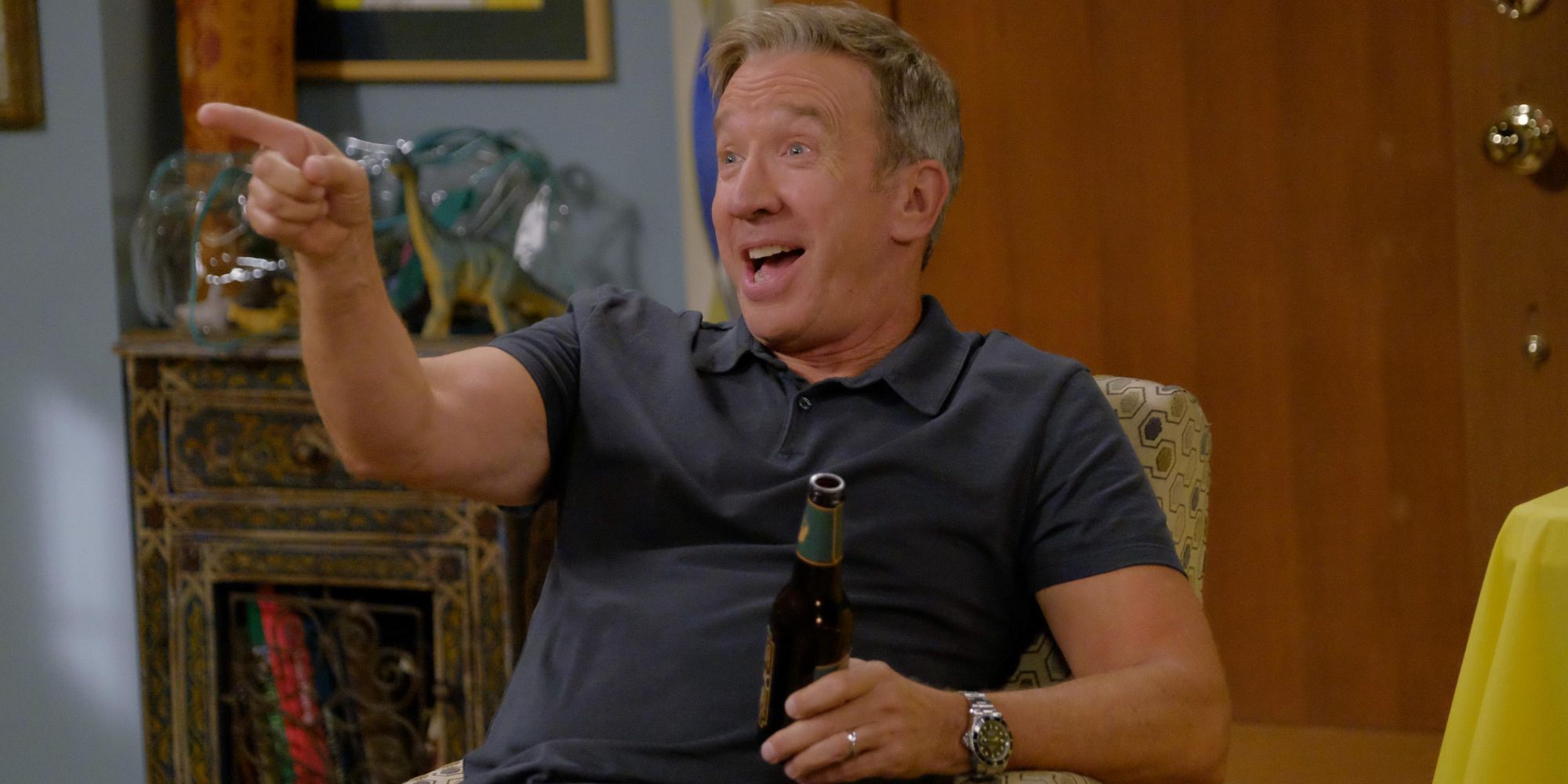 Tim Allen on Last Man Standing holding a beer and pointing while sitting down