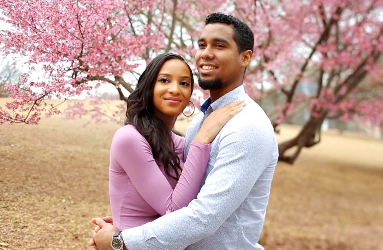 Chantel and Pedro from 90 Day Fiancé embrace and smile for the camera in front of a tree with pink blossoms.