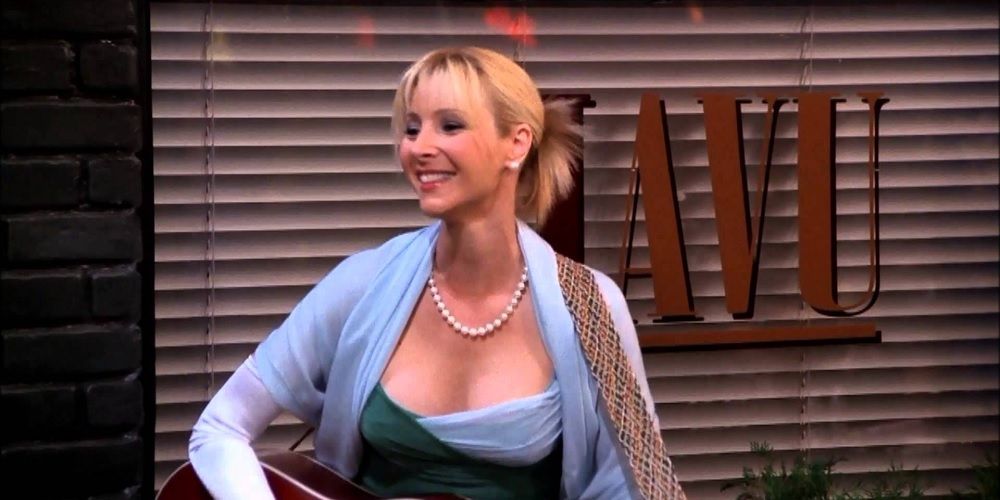 Phoebe Buffay wearing a dress and smiling while playing the guitar in Friends