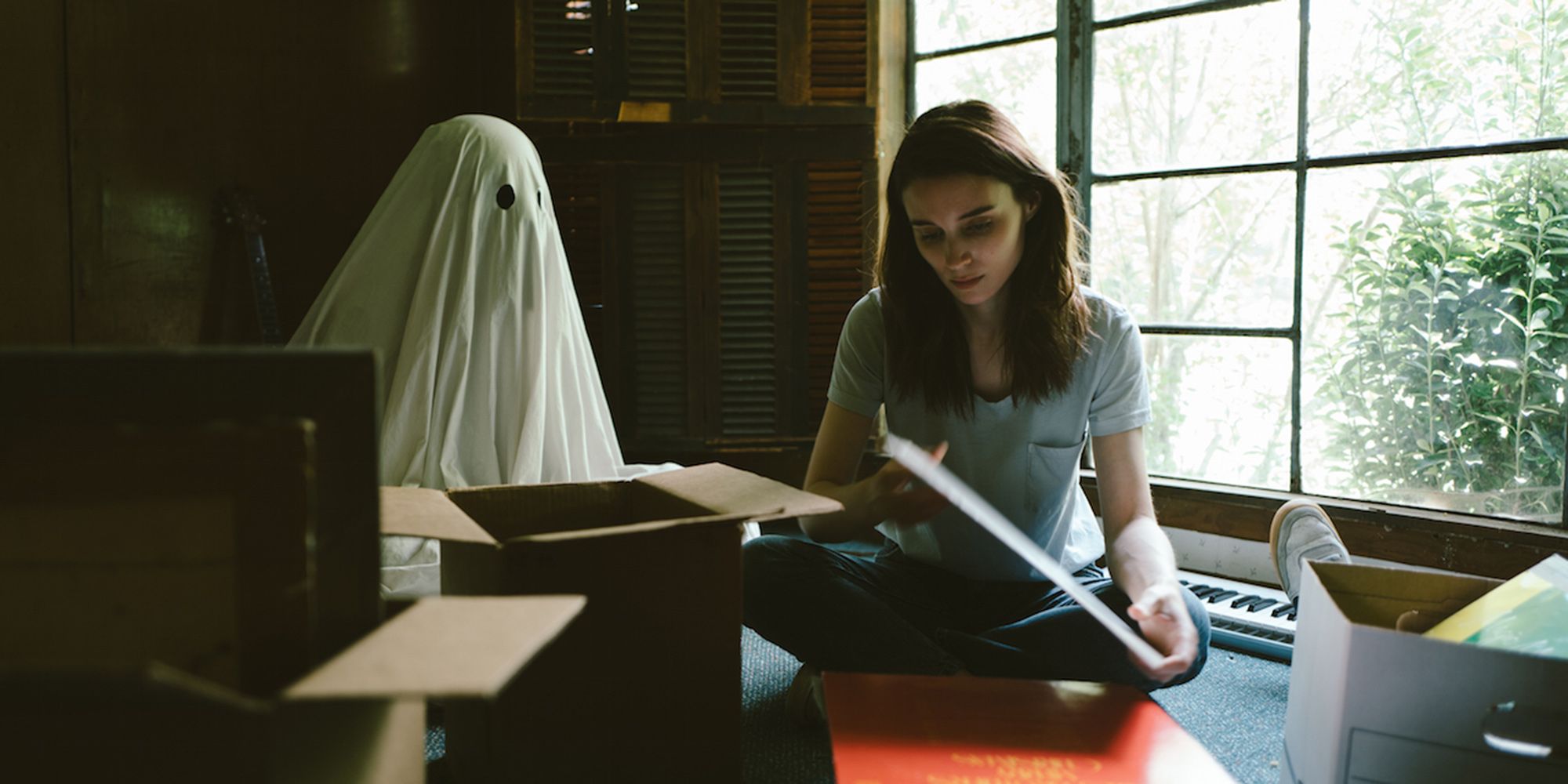 M reading a book while M stands behind her in A Ghost Story,