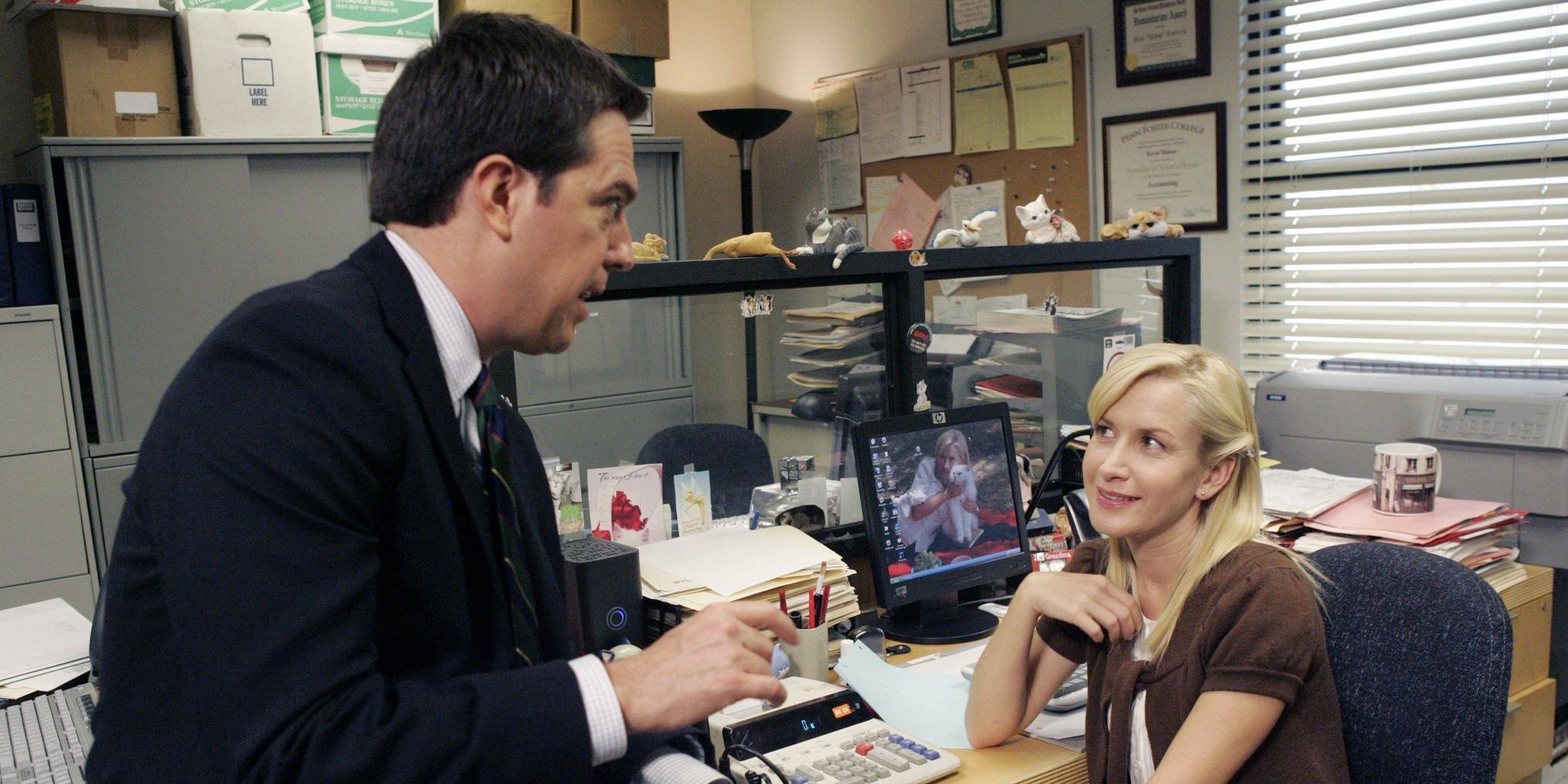 Andy and Angela talking over her desk in The Office