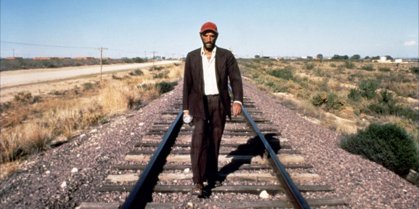 Harry Dean Stanton walks along a train track in Paris Texas