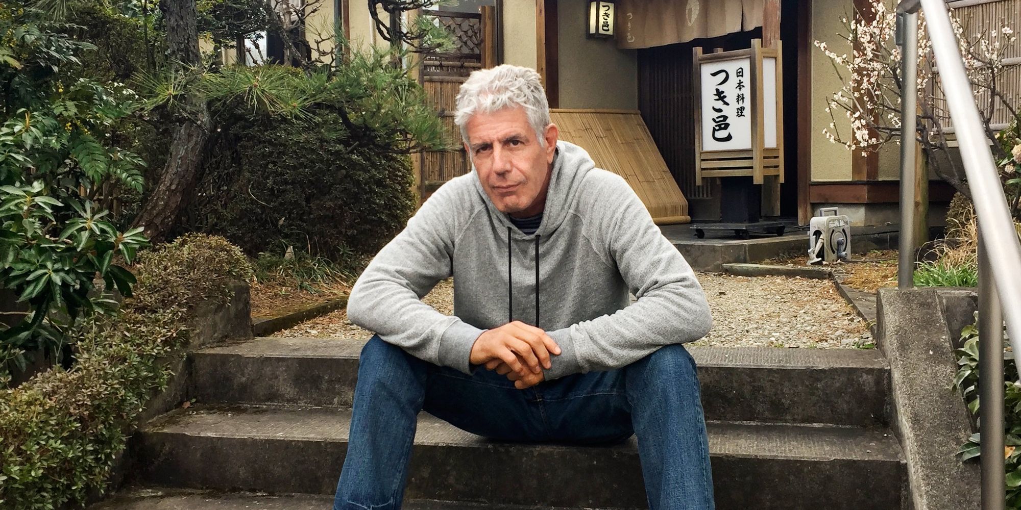 Anthony Bourdain sits on a stoop and poses for a picture 