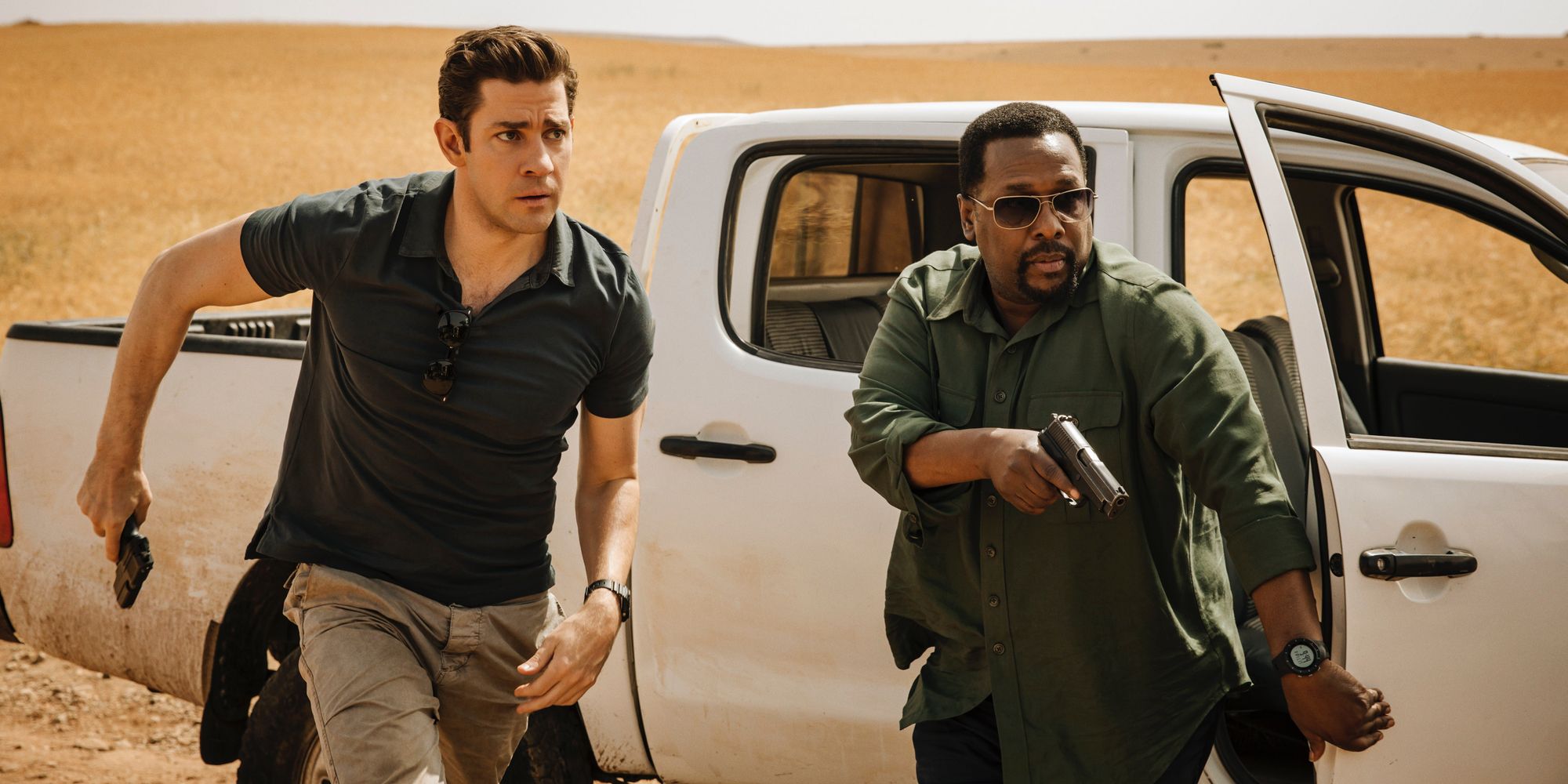 John Krasinski e Wendell Pierce saem correndo de um caminhão branco.