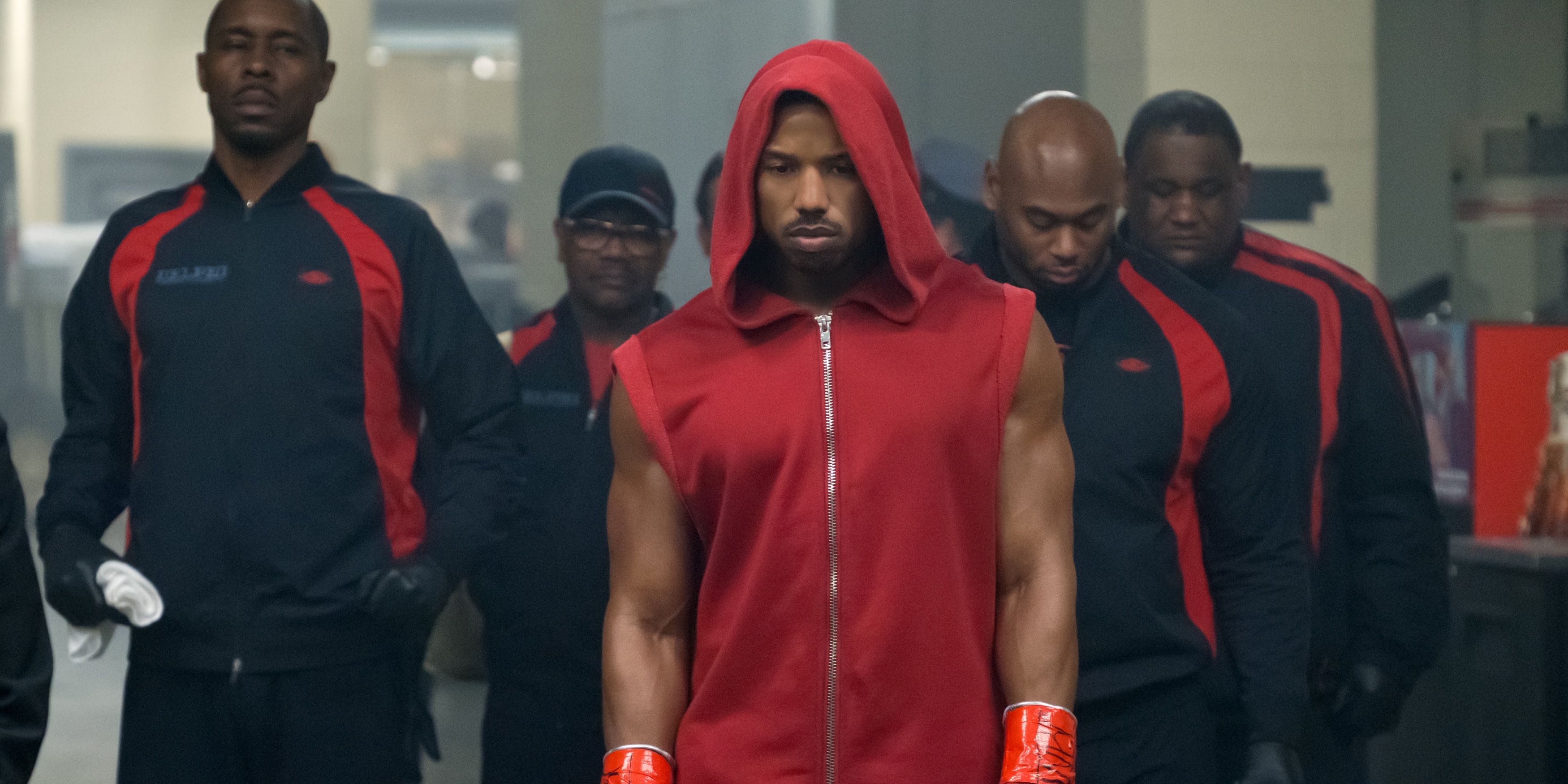 Michael B Jordan as Donnie Creed walking to a fight surrounded by his team.