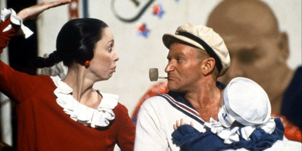 Popeye is standing with Olive and dressed as a sailor