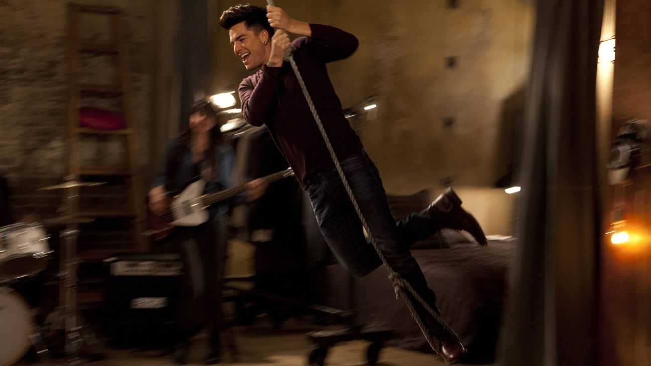 Adam Lambert swinging by a chandelier in a still from Glee