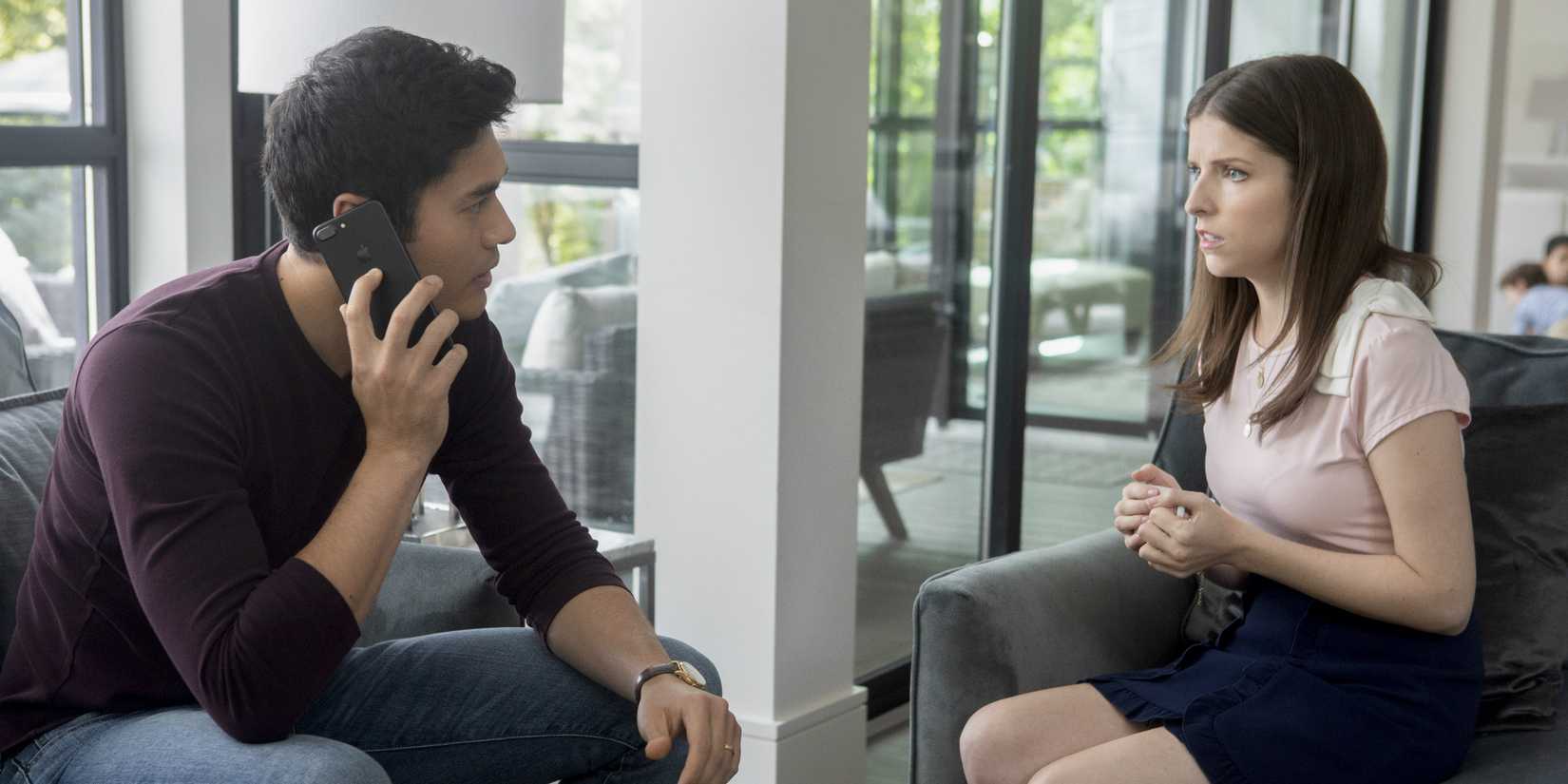 Henry Golding talks the phone while Anna Kendrick pleads with him in A Simple Favor
