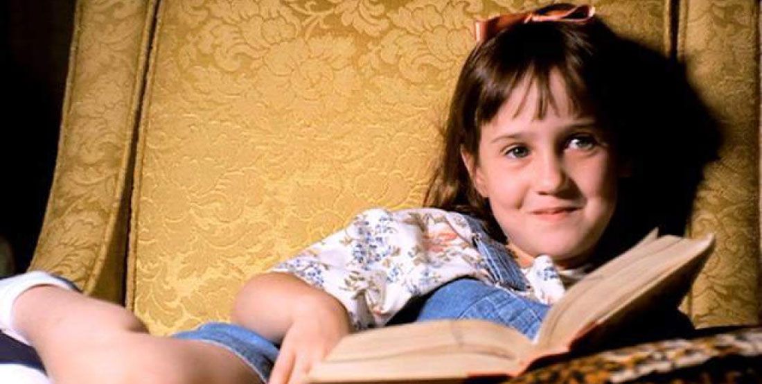 Matilda smiles while holding a book from Matilda 
