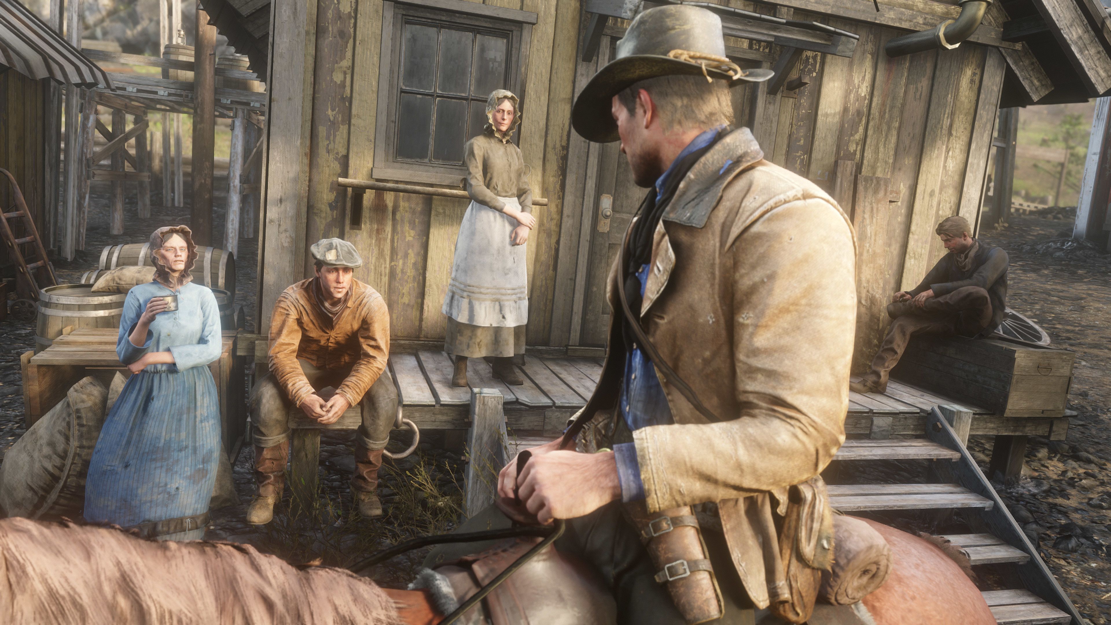 Arthur Morgan mira a algunas personas sentadas en un porche a caballo en Annesburg en Red Dead Redemption 2