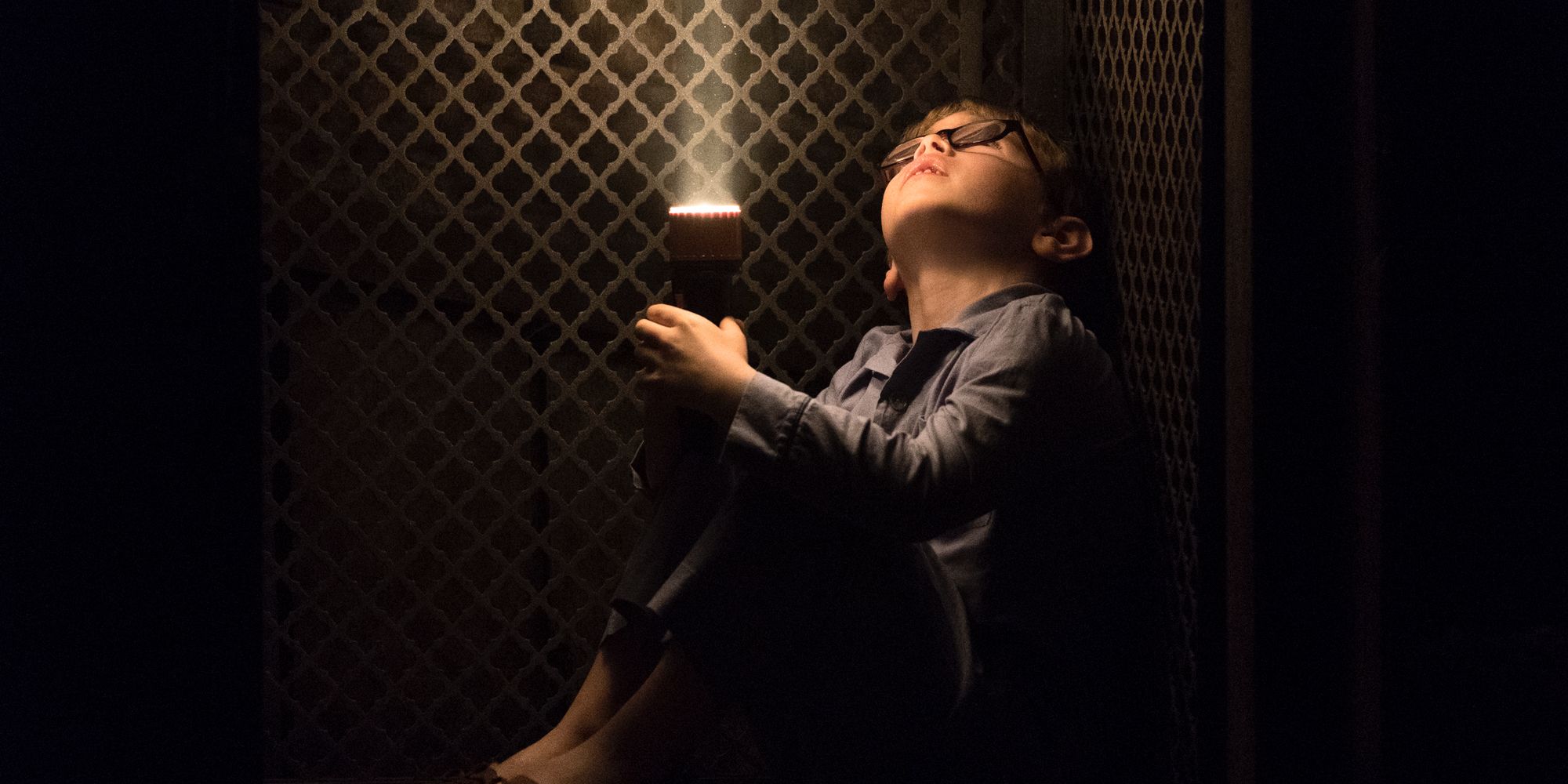 A young Luke looks up with a flashlight in The Haunting of Hill House