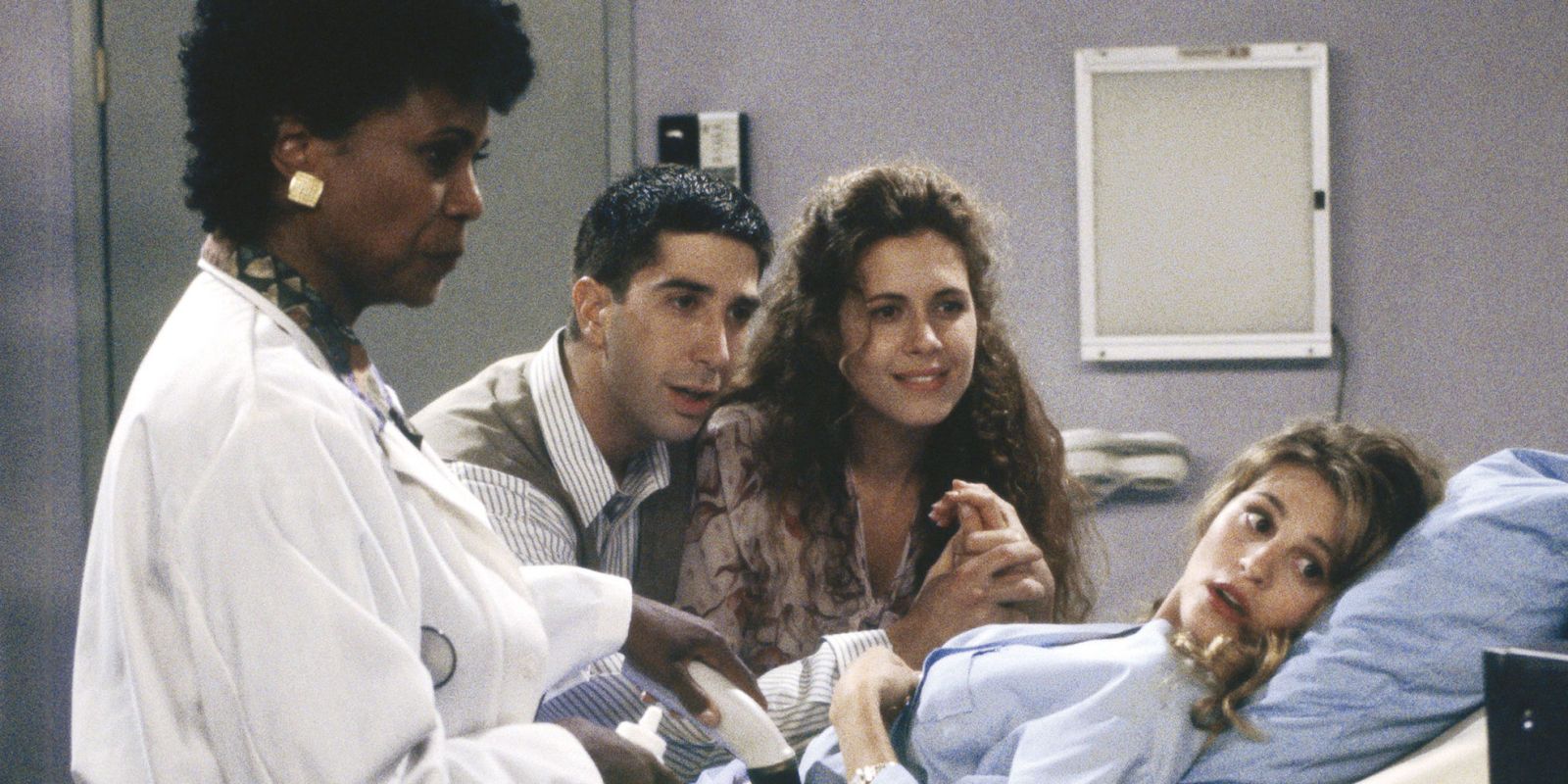 Jane Sibbett as Carol giving birth surrounded by Jessica Hecht as Susan, David Schwimmer as Ross, and a doctor in Friends