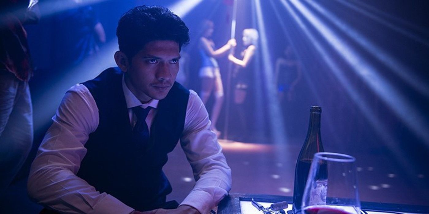 Iko sits in a nightclub with dancers behind him in The Night Comes for Us.