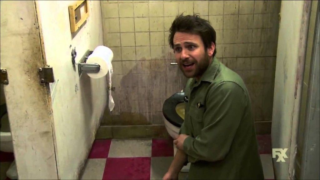 Charlie Kelly leaning in from of toilet in bathroom stall